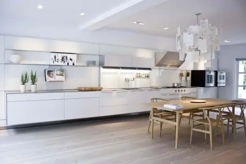 Cucina moderna e minimalista, con mobili bianchi lineari e un tavolo in legno. Un esempio di come progettare una cucina funzionale ed elegante.
