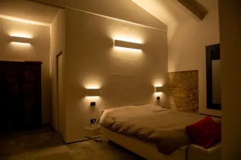 Moderne idee illuminazione led soggiorno: applique a parete creano un'atmosfera calda e accogliente attorno al letto.