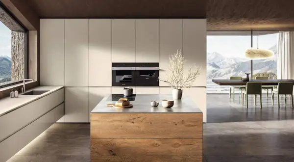 Elegante cucina bianca e legno naturale con isola centrale. Ampia finestra con vista panoramica sulle montagne.