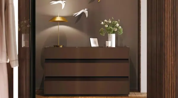 Cosa mettere sul como' della camera da letto moderna: lampada dorata, fiori in vaso bianco, cornice e candela.