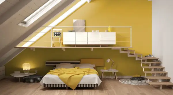Camera da letto moderna con pareti in varie tonalità di giallo, un letto con coperta gialla e una scala a vista.