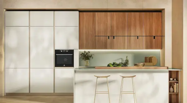 Cucina tutta altezza con ante bianche e pensili in legno. Forno integrato, isola con sgabelli dorati e dettagli verdi.