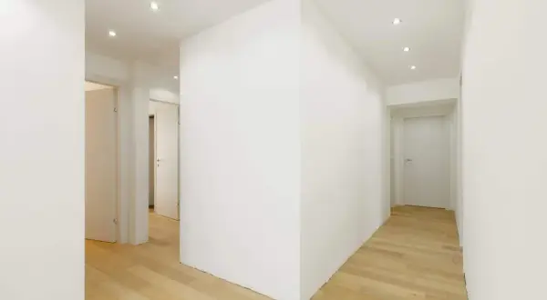 Un moderno ingresso con un divisorio in cartongesso che crea un'elegante separazione. Le idee per l'ingresso sono valorizzate dal design pulito e dai pavimenti in legno chiaro.