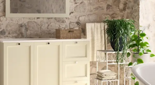 Bagni stile rustico con mobile lavabo color crema, pareti in pietra grezza e piante verdi.