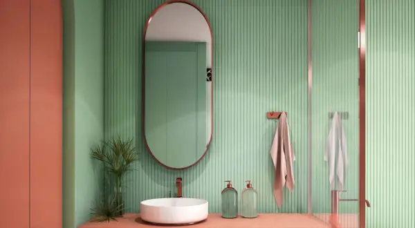 Bagno moderno con lavabo bianco, mobile color pesca e pareti verdi a coste. Idee bagni piccoli bellissimi con specchio ovale e dettagli in rame.