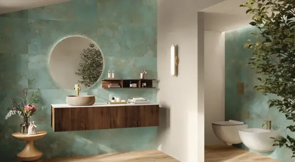 Elegante bagno verde petrolio e legno con lavabo in pietra, specchio rotondo e sanitari sospesi.