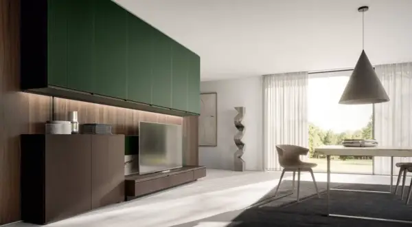 Soggiorno moderno con pensili verde foresta, mobile TV in legno scuro, scultura astratta e tavolo da pranzo con vista sul giardino.