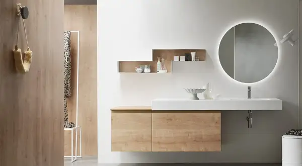 Bagno effetto legno e bianco: mobile sospeso, lavabo bianco, specchio rotondo illuminato e pareti in legno creano un ambiente moderno e accogliente.