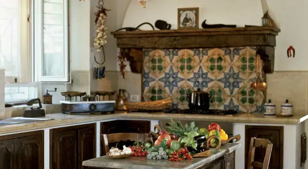 Cucine montagna piccole con un ricco tavolo di verdure fresche. Pareti decorate con maioliche colorate e dettagli rustici.