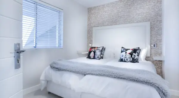 Camera da letto moderna con cuscini di Marilyn Monroe. I colori neutri e la luce soffusa creano un'atmosfera rilassante, perfetta per la cromoterapia.
