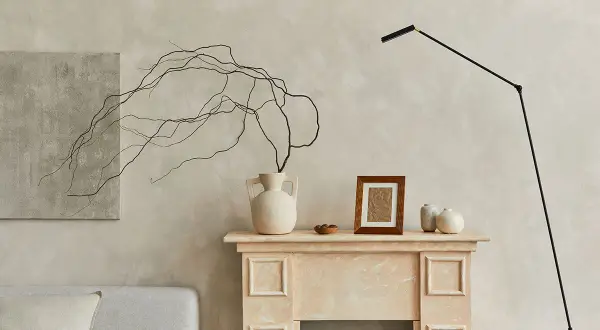 Un camino decorato con vasi, un quadro e rami secchi, perfetto per decorare una parete spoglia.