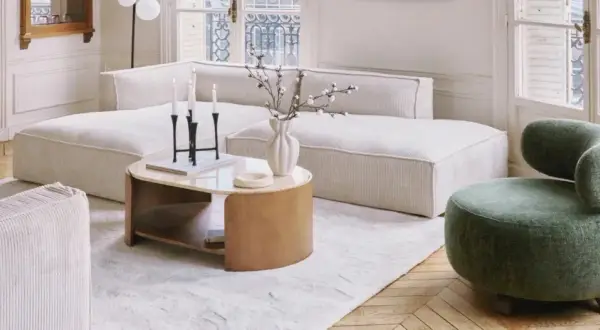 Tavolino con finitura in legno betulla colore, accanto a un divano bianco e una poltrona verde.