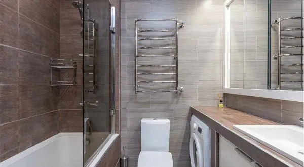 Bagno moderno con vasca, doccia, WC e una pratica lavatrice integrata sotto il lavandino.