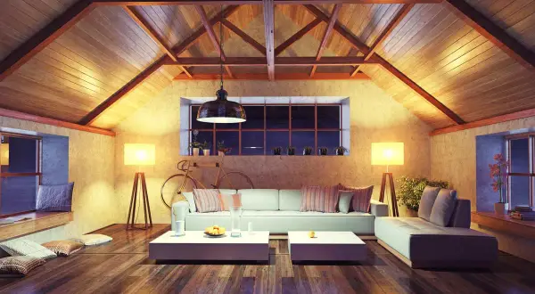 Accogliente soggiorno mansardato con travi a vista e illuminazione calda. Ottime idee sottotetto molto basso per creare un ambiente confortevole.