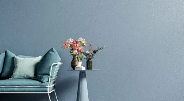 Divano turchese e tavolino con fiori su sfondo blu polvere, un'ispirazione per una moderno pittura cameretta.
