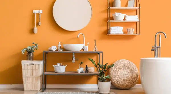 Bagno moderno con pareti arancioni vivaci, lavabo sospeso, vasca bianca e idee pittura bagno che ispirano freschezza e stile.