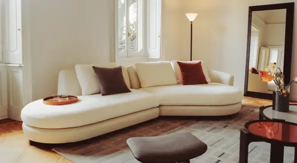 Soggiorno accogliente con divano bianco, cuscini colorati e vassoio. Un esempio di come fare decluttering per un ambiente sereno.