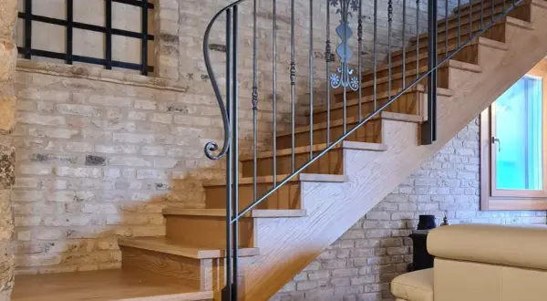 Scale interne in legno con ringhiera in ferro battuto, un'idea di design che unisce rustico e moderno.