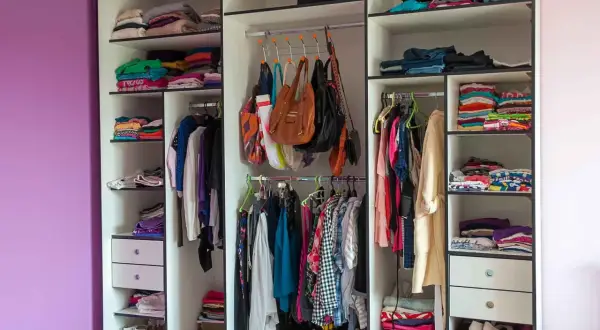 Armadio camera da letto con abiti piegati e appesi, borse e scarpe. I colori vivaci dei vestiti creano un arcobaleno.