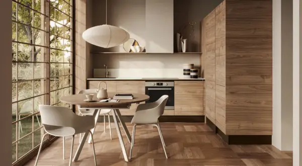 Ecco come arredare una cucina moderna: mobili in legno, tavolo rotondo con sedie bianche e grande finestra con vista sul verde.