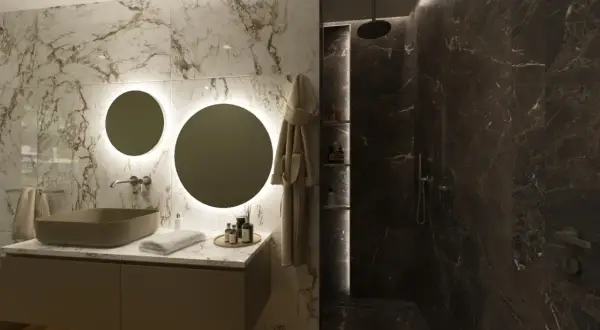 Elegante bagno scuro moderno con lavabo in pietra, specchi rotondi illuminati e doccia in marmo scuro.