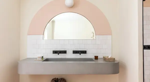 Lavabo bagno in muratura moderno con doppio rubinetto nero e specchio ad arco. Idee per un bagno di design.