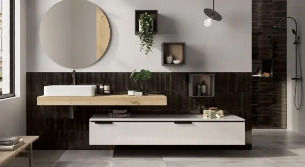 Bagno moderno con piastrelle nere verticali, lavabo bianco su mensola in legno, specchio rotondo e mobile sospeso. Idee bagno nero e legno per un look sofisticato.