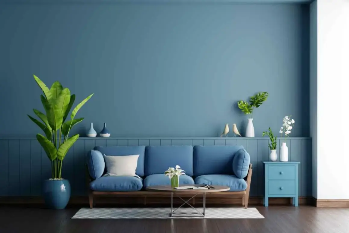 Soggiorno con divano blu e pareti color carta da zucchero. Piante verdi e decorazioni creano un'atmosfera rilassante.