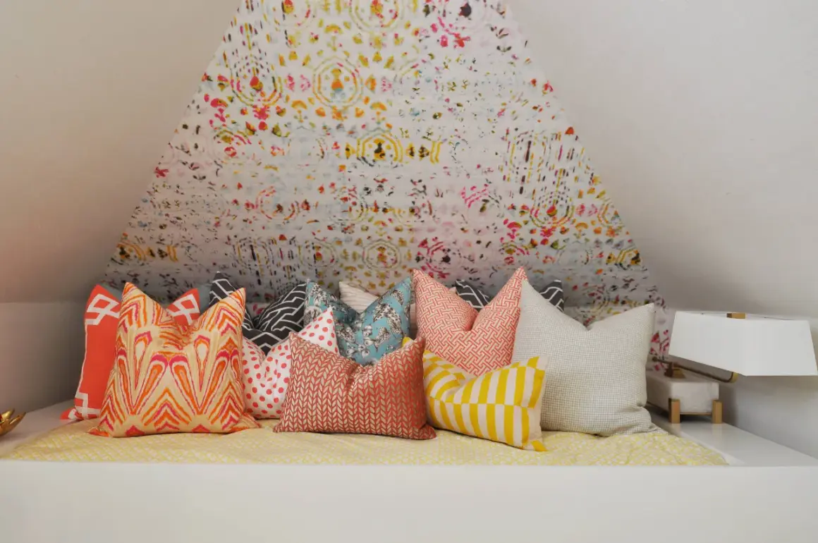 Un letto accogliente con tanti cuscini decorativi dai motivi vivaci e colorati, pronti per un riposo da sogno.