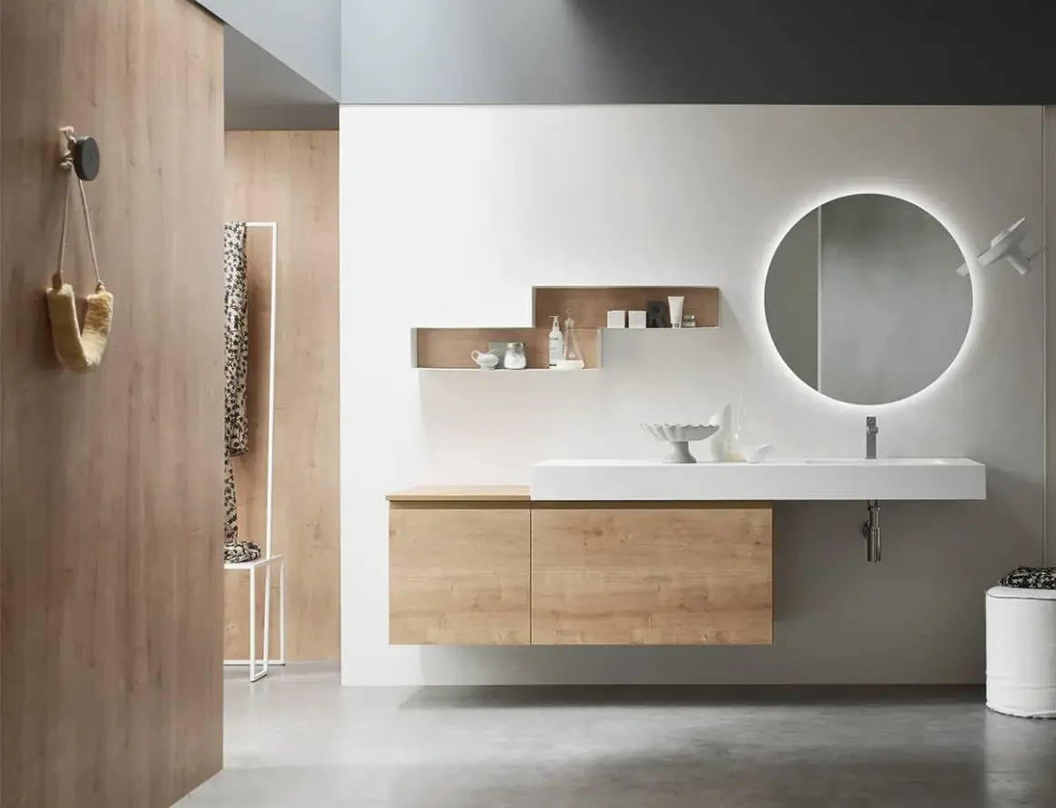 Bagno effetto legno e bianco: mobile sospeso, lavabo bianco, specchio rotondo illuminato e pareti in legno creano un ambiente moderno e accogliente.