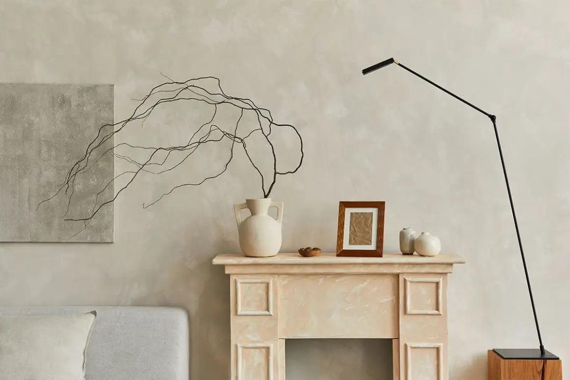 Un camino decorato con vasi, un quadro e rami secchi, perfetto per decorare una parete spoglia.