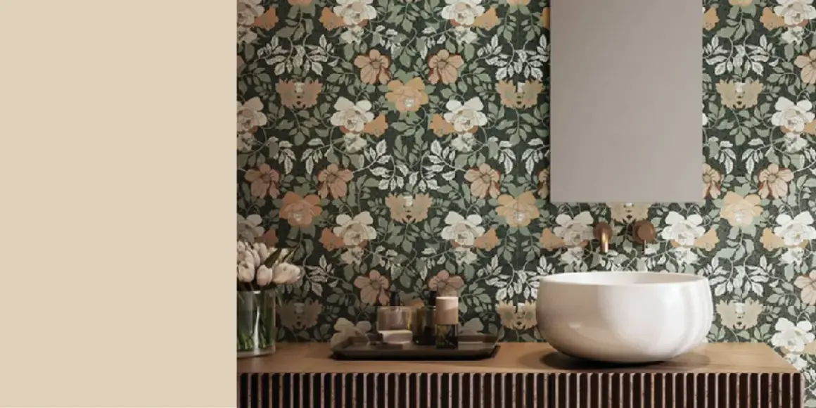 Bagno con carta da parati floreale su sfondo verde scuro, fiori bianchi e color sabbia. Lavabo bianco, specchio e rubinetteria dorata.