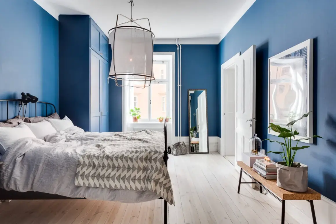 Accogliente camera da letto blu con letto matrimoniale, armadio blu e specchio a figura intera.
