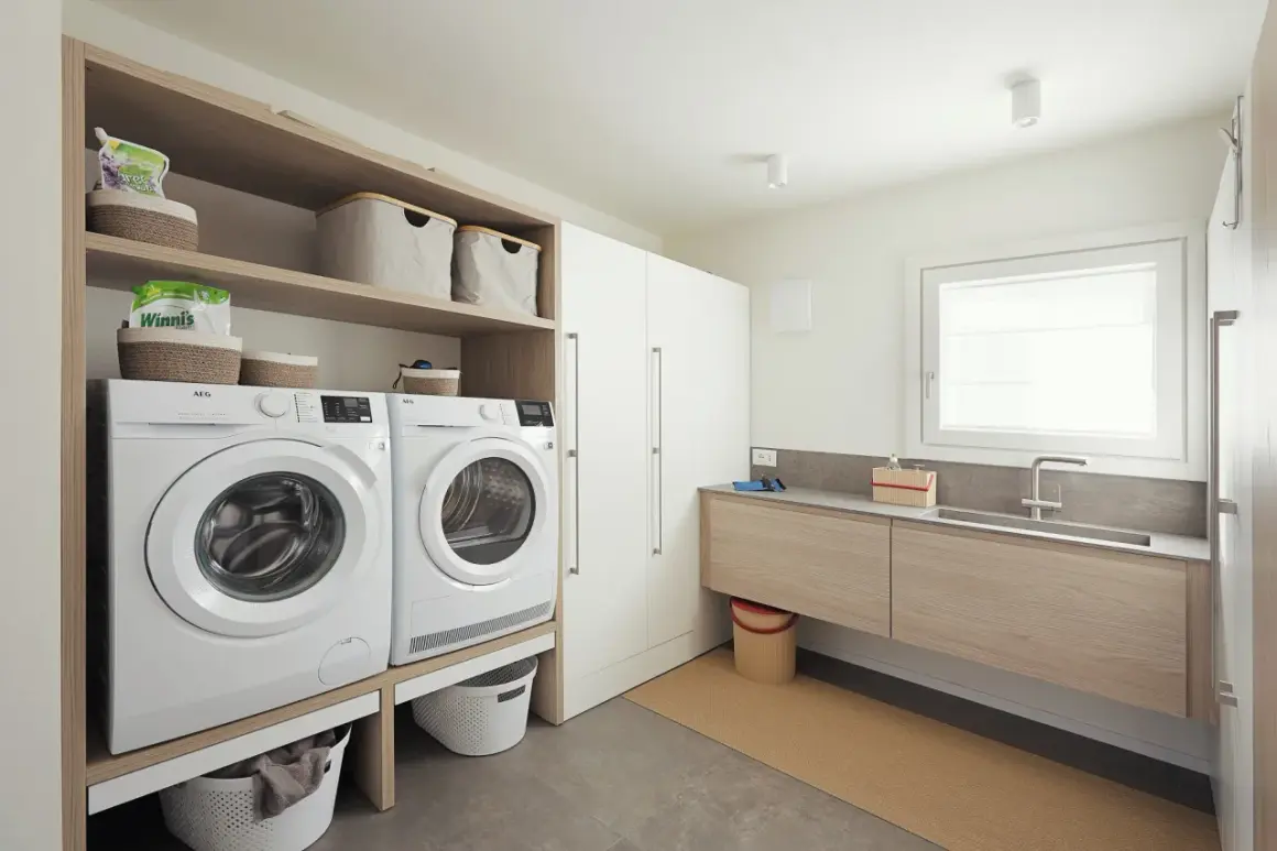 Progetto bagno con lavanderia: lavatrice, asciugatrice, lavabo e armadi, tutto organizzato per un ambiente funzionale.