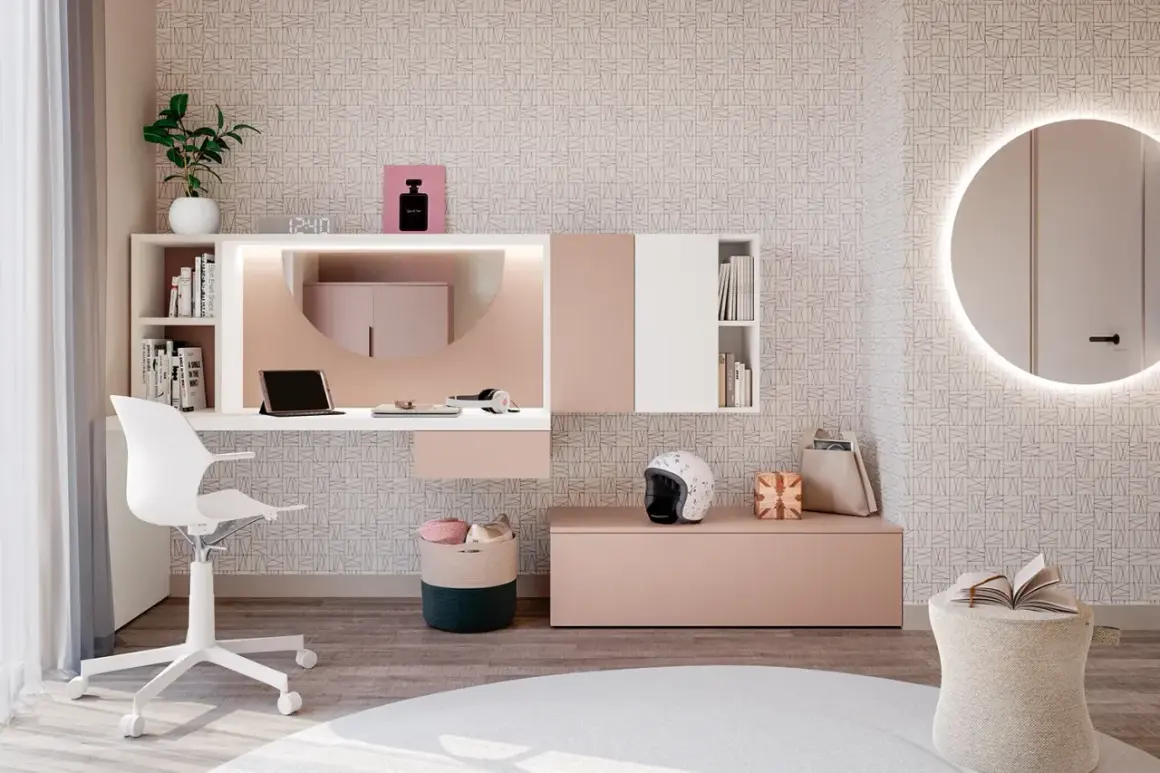 Moderna postazione trucco con specchio rotondo illuminato, scrivania bianca e rosa, sedia, cestini e decorazioni.