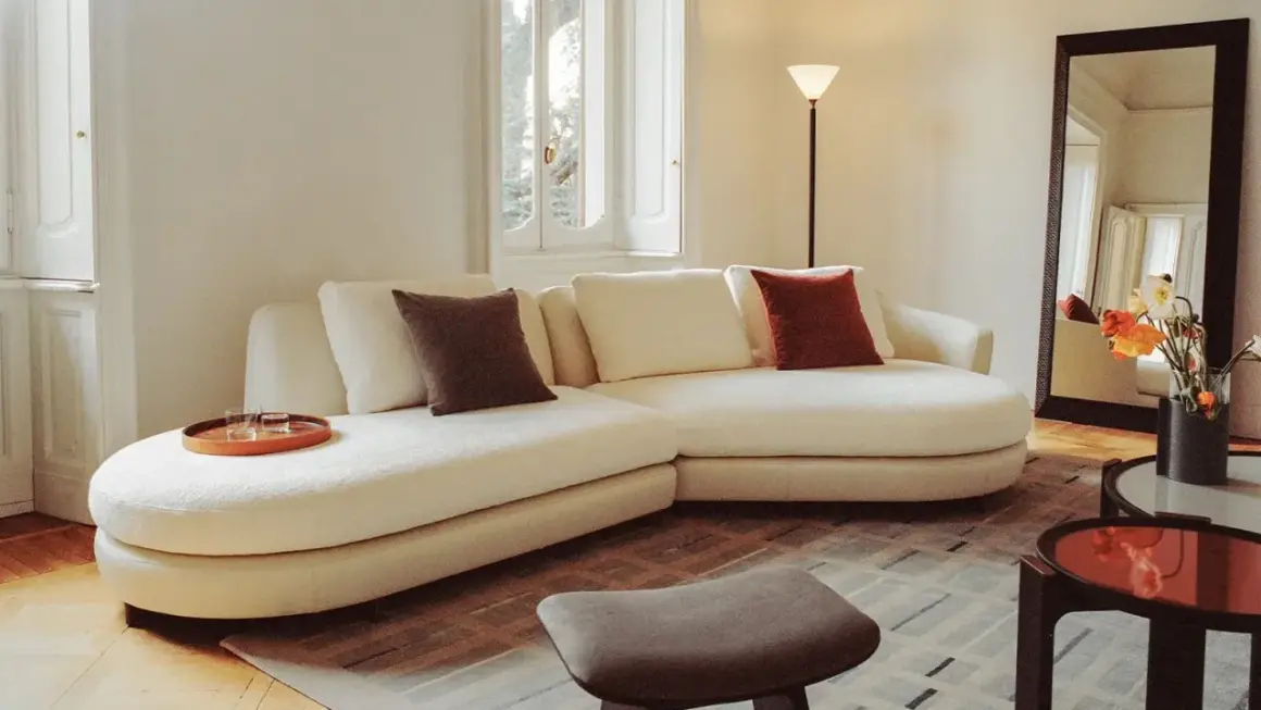 Soggiorno accogliente con divano bianco, cuscini colorati e vassoio. Un esempio di come fare decluttering per un ambiente sereno.