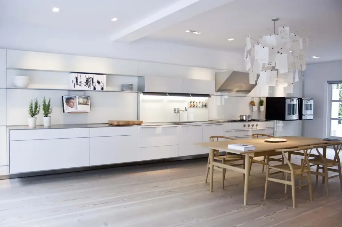 Cucina moderna e minimalista, con mobili bianchi lineari e un tavolo in legno. Un esempio di come progettare una cucina funzionale ed elegante.