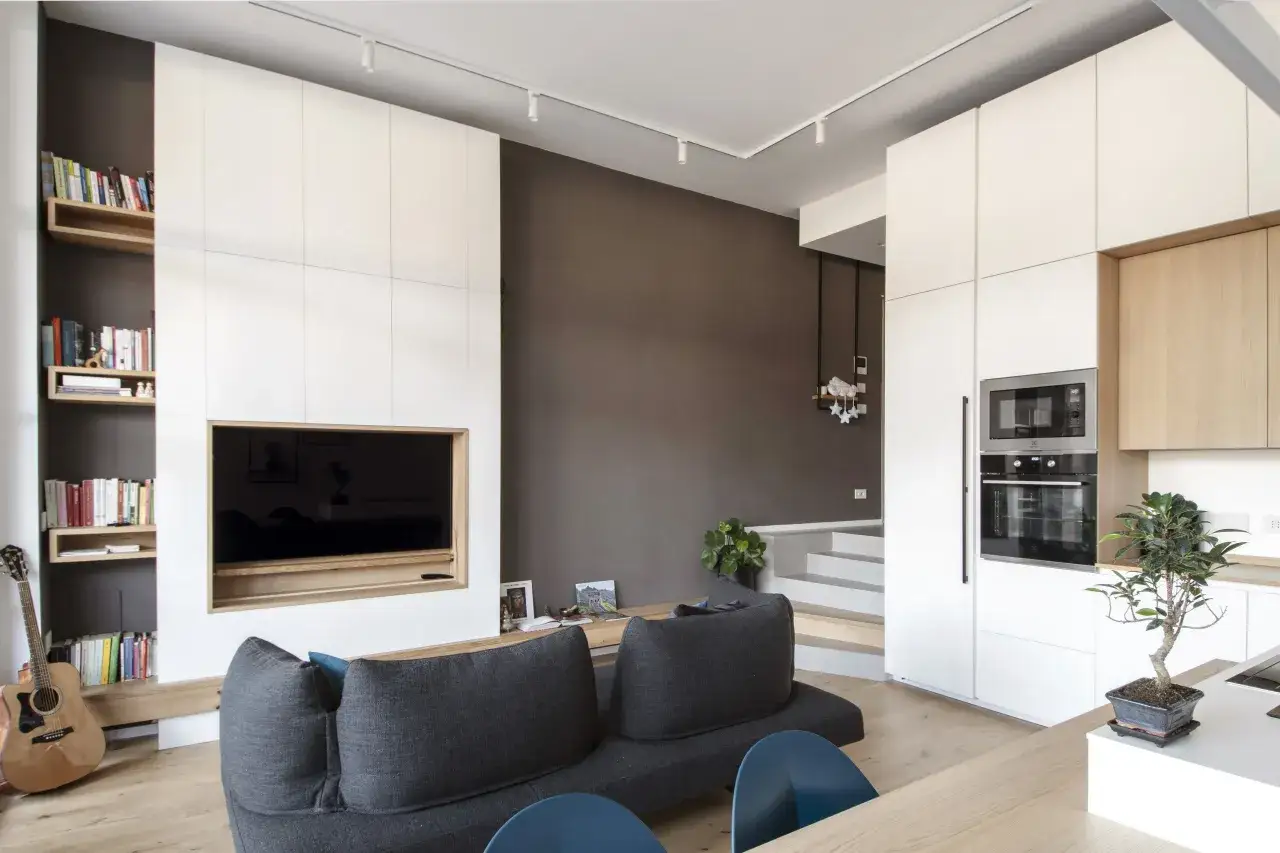 Interni moderni per un progetto casa 70 mq rettangolare: divano grigio, libreria, TV a incasso, cucina bianca e scala.