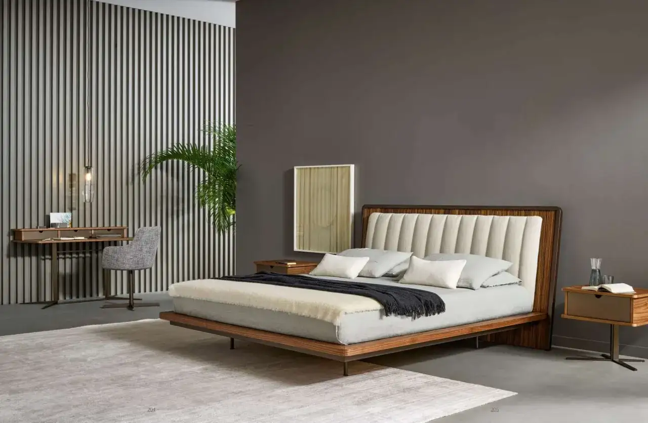Camera da letto con pareti grigio scuro e mobili chiari. Letto moderno con testiera imbottita, comodino in legno e scrivania con sedia.