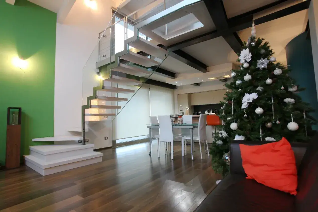 Moderna scala in legno e vetro, con un albero di Natale addobbato. Ottime idee per soppalco in legno.