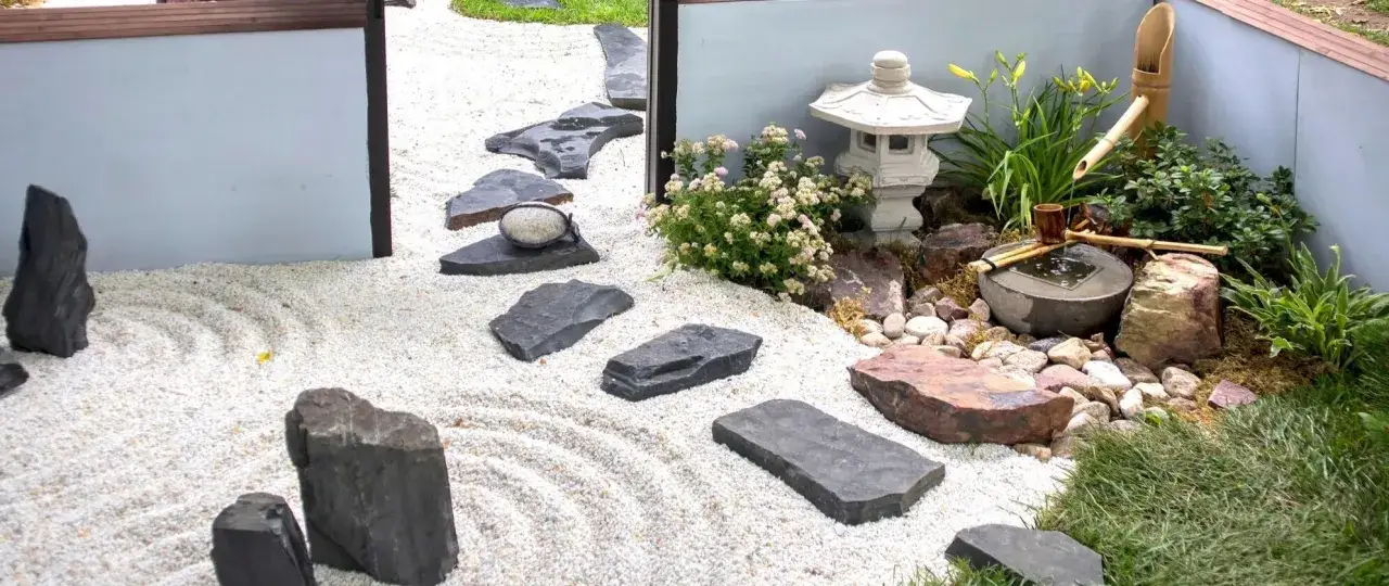 Un angolo di pace: un giardino zen in casa con ghiaia rastrellata, pietre scure, una lanterna e una piccola fontana di bamb&ugrave;.