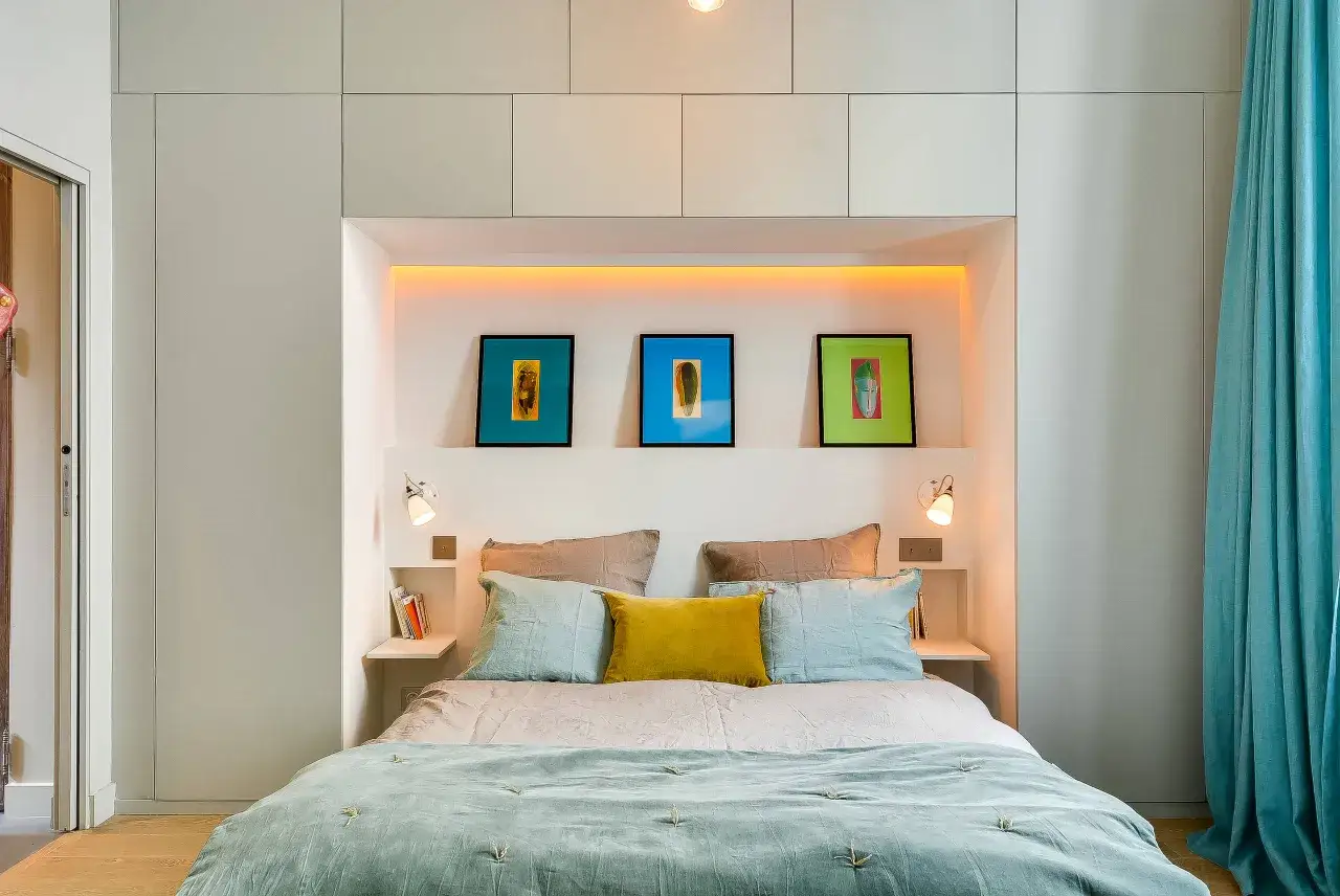 Letto con testiera incassata, tre quadri colorati e comodini a muro, perfetto se non ho spazio per i comodini.