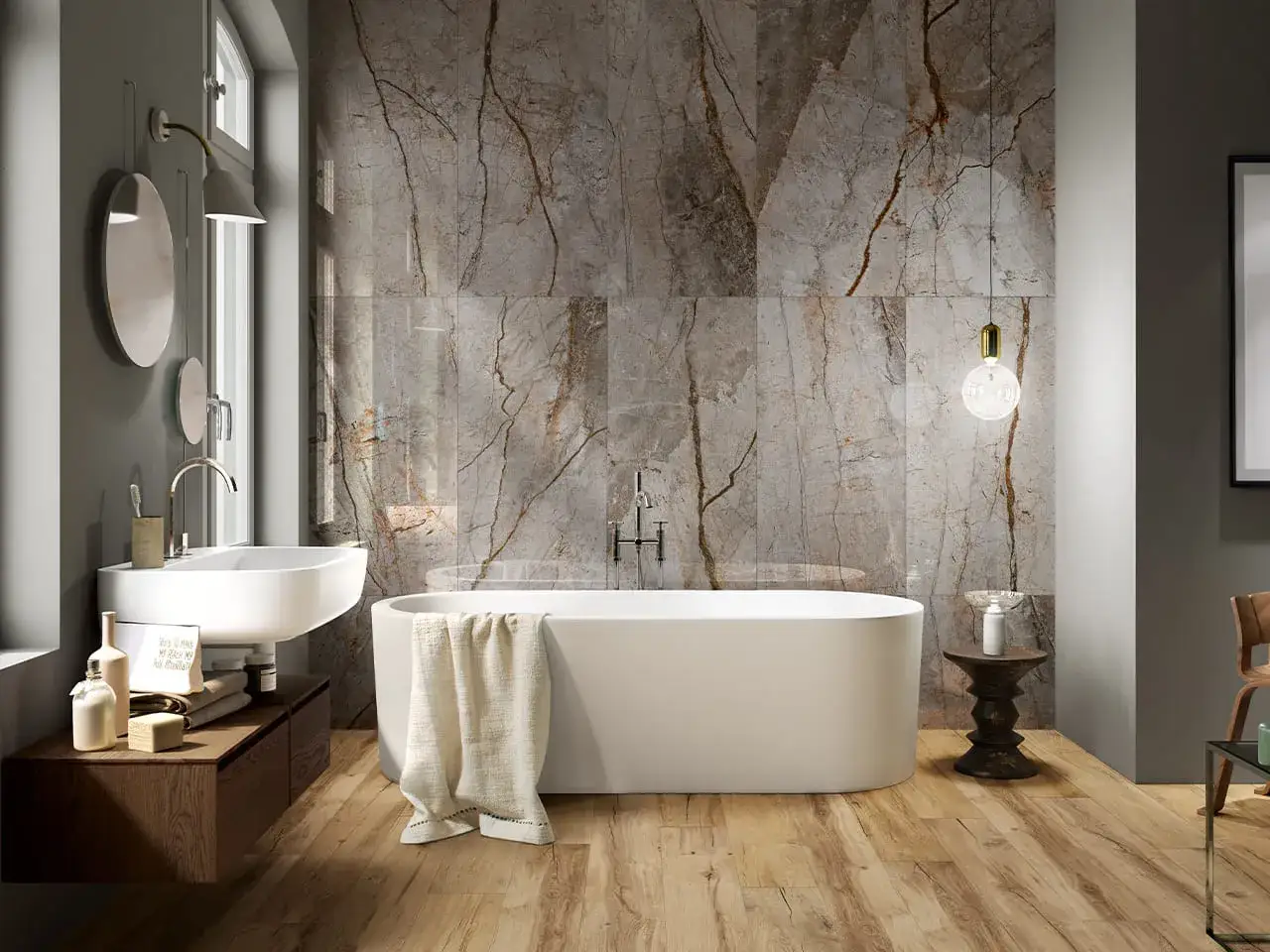 Bagno moderno con vasca freestanding e lavabo sospeso. Parete rivestita con lastre in gres porcellanato effetto marmo, un'idea di lusso.