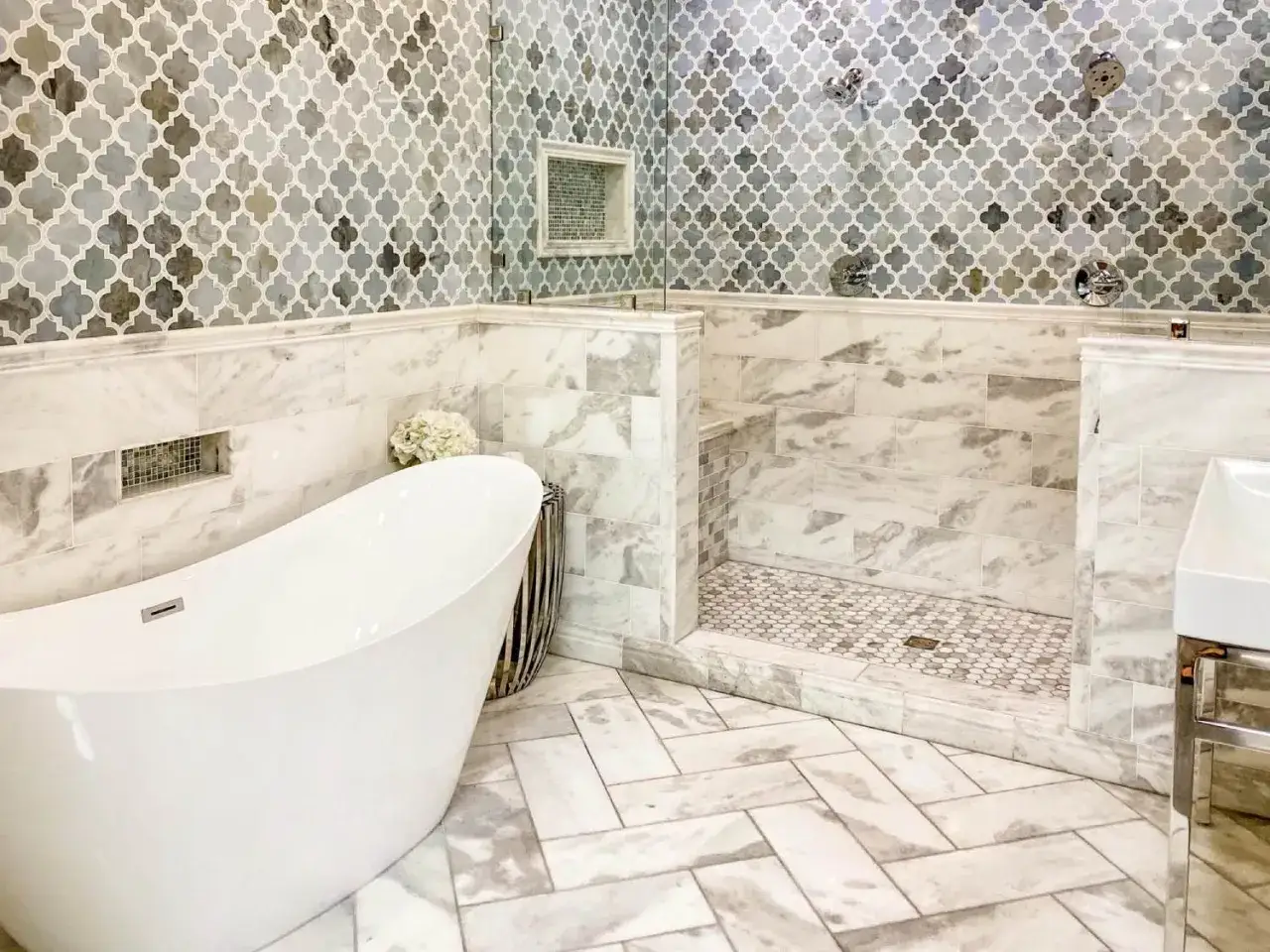 Bagno moderno con vasca freestanding e doccia a nicchia. Le pareti sono rivestite con eleganti piastrelle a mosaico e marmo, creando splendide idee bagno piastrelle.