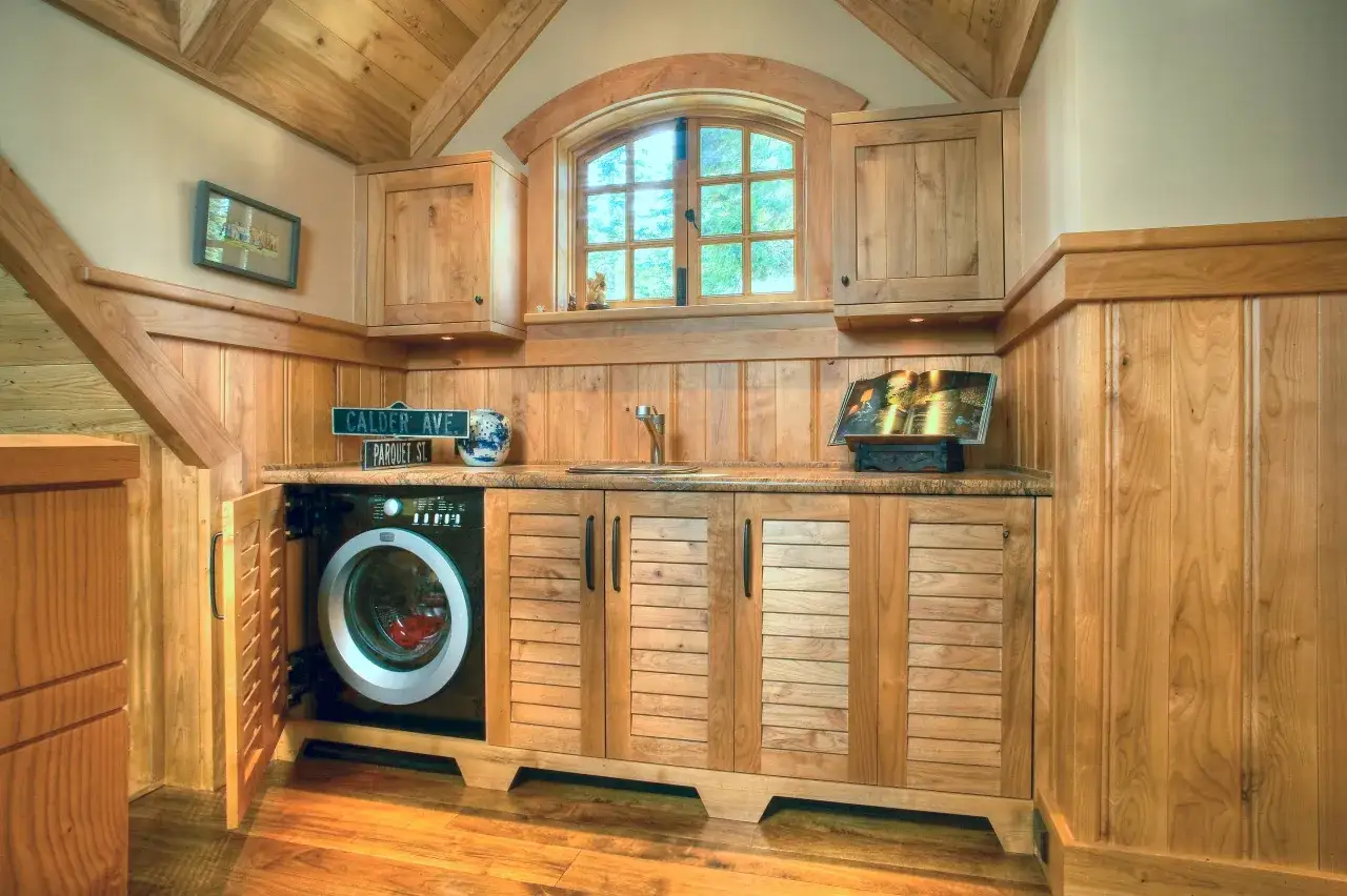 Soluzione elegante per come nascondere lavatrice e asciugatrice in un mobile di legno con ante a persiana, integrato in un ambiente accogliente.