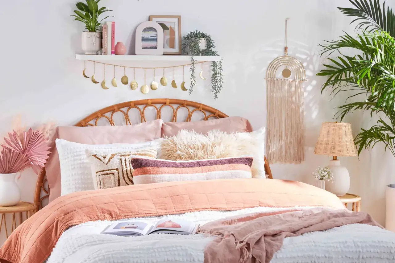 Camera ragazza aesthetic con letto in rattan, cuscini color pesca e macram&egrave;. Ghirlanda di lune dorate sopra il letto.