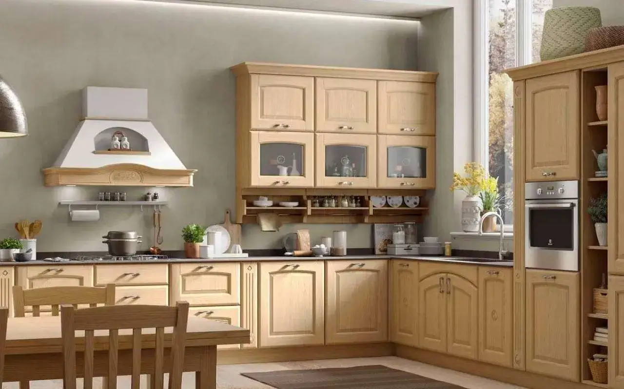 Cucine montagna piccole in legno chiaro, con cappa bianca, pensili con ante in vetro e piano di lavoro scuro.