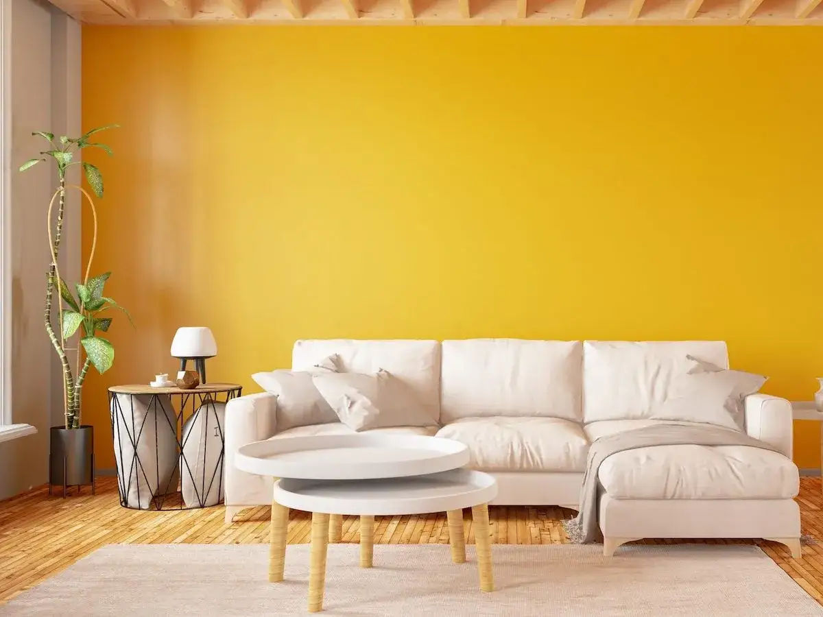 Soggiorno con divano bianco e parete giallo sole. Le tonalit&agrave; di giallo nomi evocano allegria e calore, creando un ambiente accogliente.