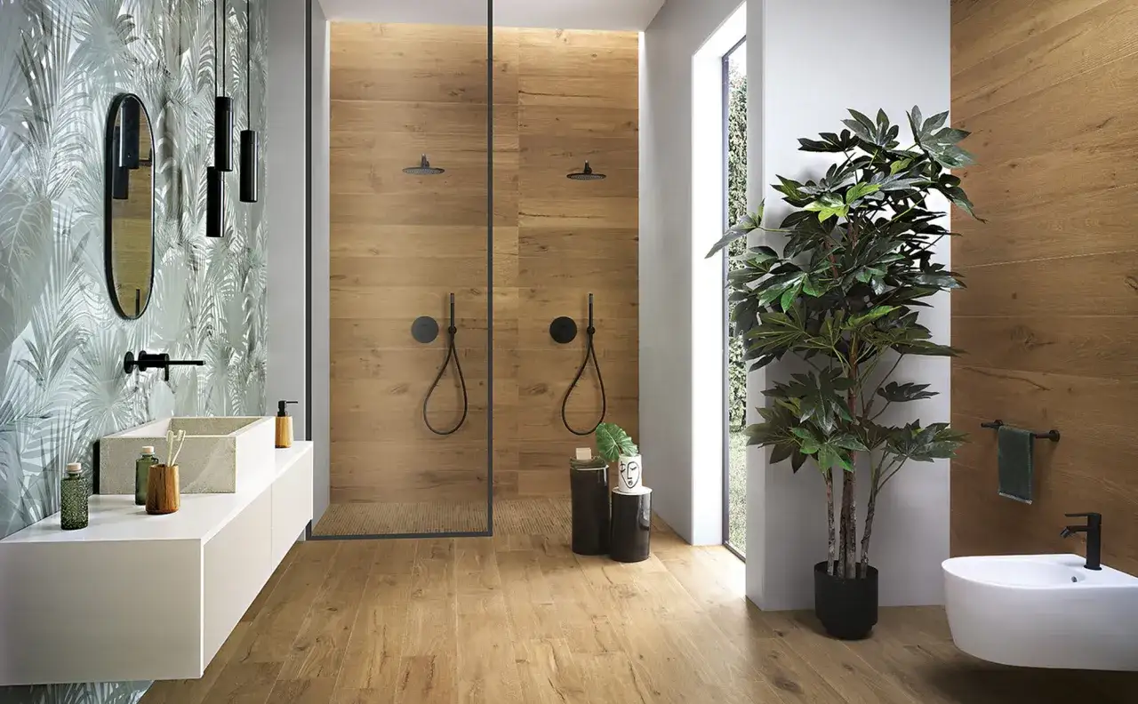 Un bagno minimal con doccia doppia in legno, lavabo sospeso, carta da parati tropicale e una grande pianta verde.