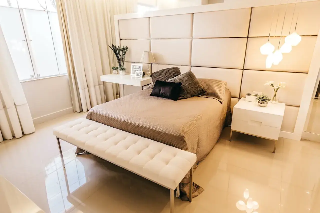Un letto accogliente con un copriletto beige e cuscini decorativi, tra cui uno nero e uno grigio lavorato a maglia.
